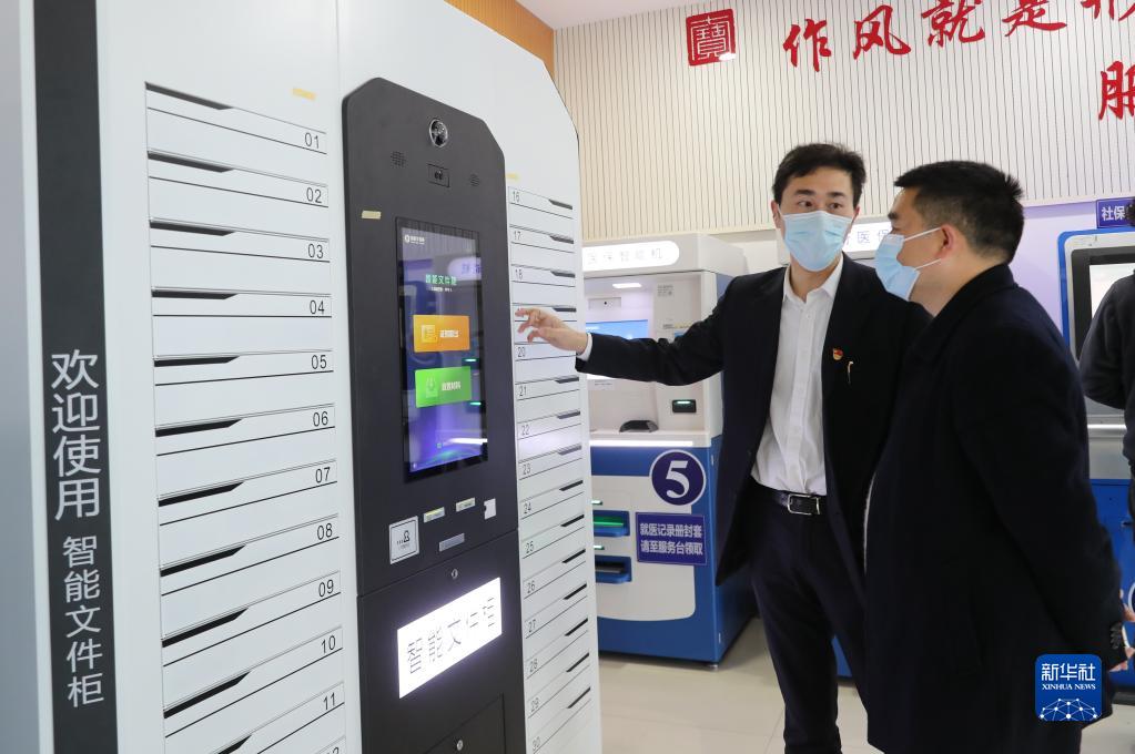 上海市闵行区七宝镇社区事务受理服务中心的工作人员(左)向前来办事的居民介绍智能文件柜的使用方法(2021年3月3日摄)。